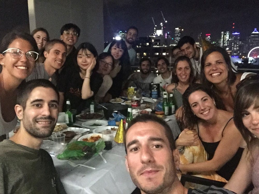 fotografía de un grupo de amigos sentados en una mesa y sonriendo a cámara